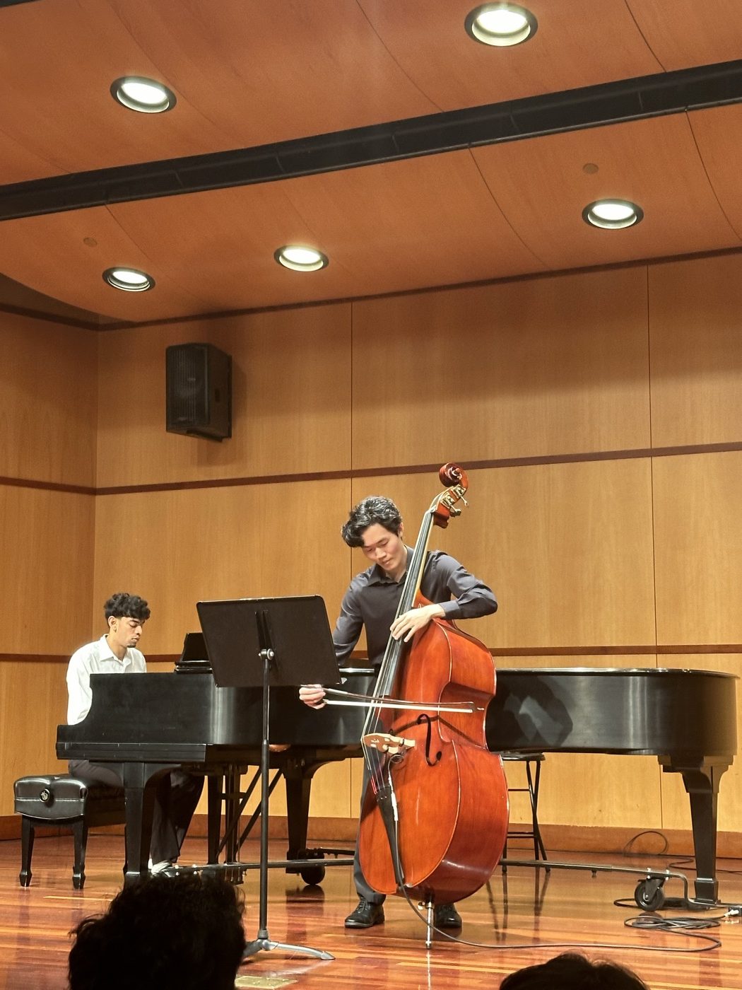 Gordon playing upright bass with a bow on stage, with a pianist accompanying